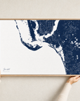 Sanibel canvas map — hands holding the canvas in an oak frame