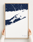The Hamptons canvas map — hands holding the canvas in an oak frame