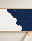 Central California Coast canvas map — hands holding the canvas in an oak frame