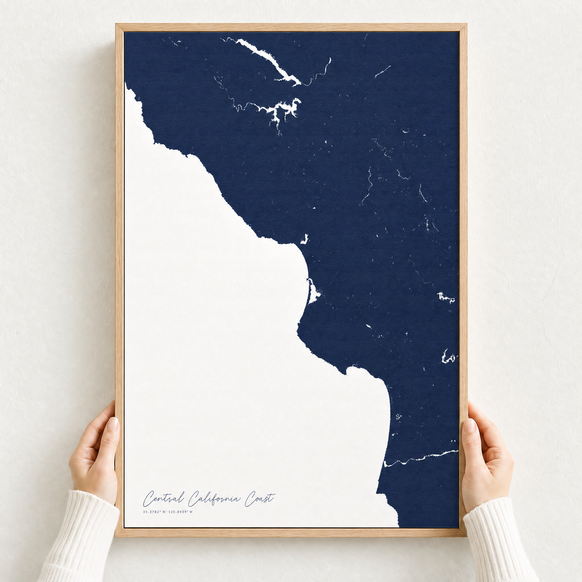 Central California Coast canvas map — hands holding the canvas in an oak frame
