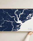 Charleston canvas map — hands holding the canvas in an oak frame
