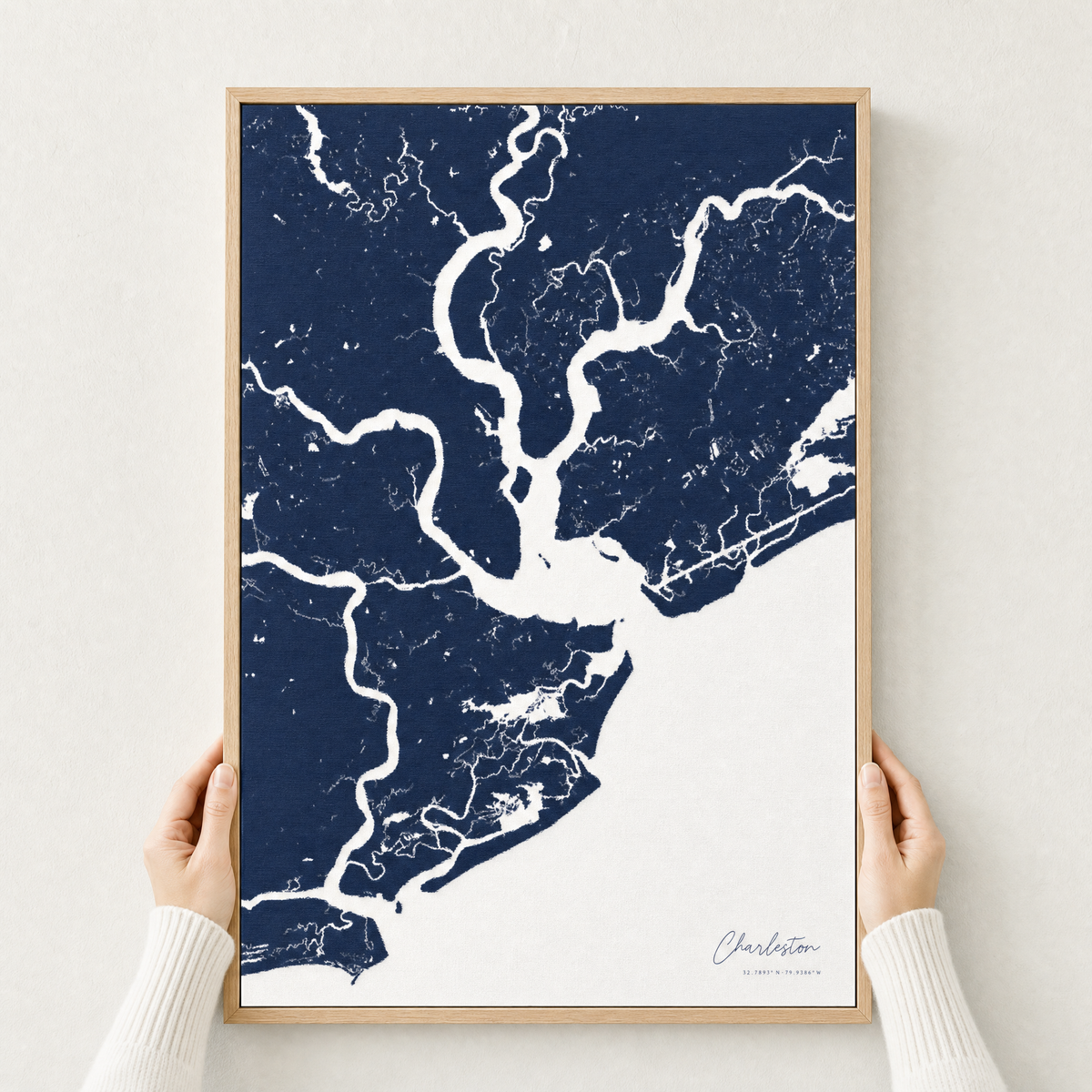 Charleston canvas map — hands holding the canvas in an oak frame