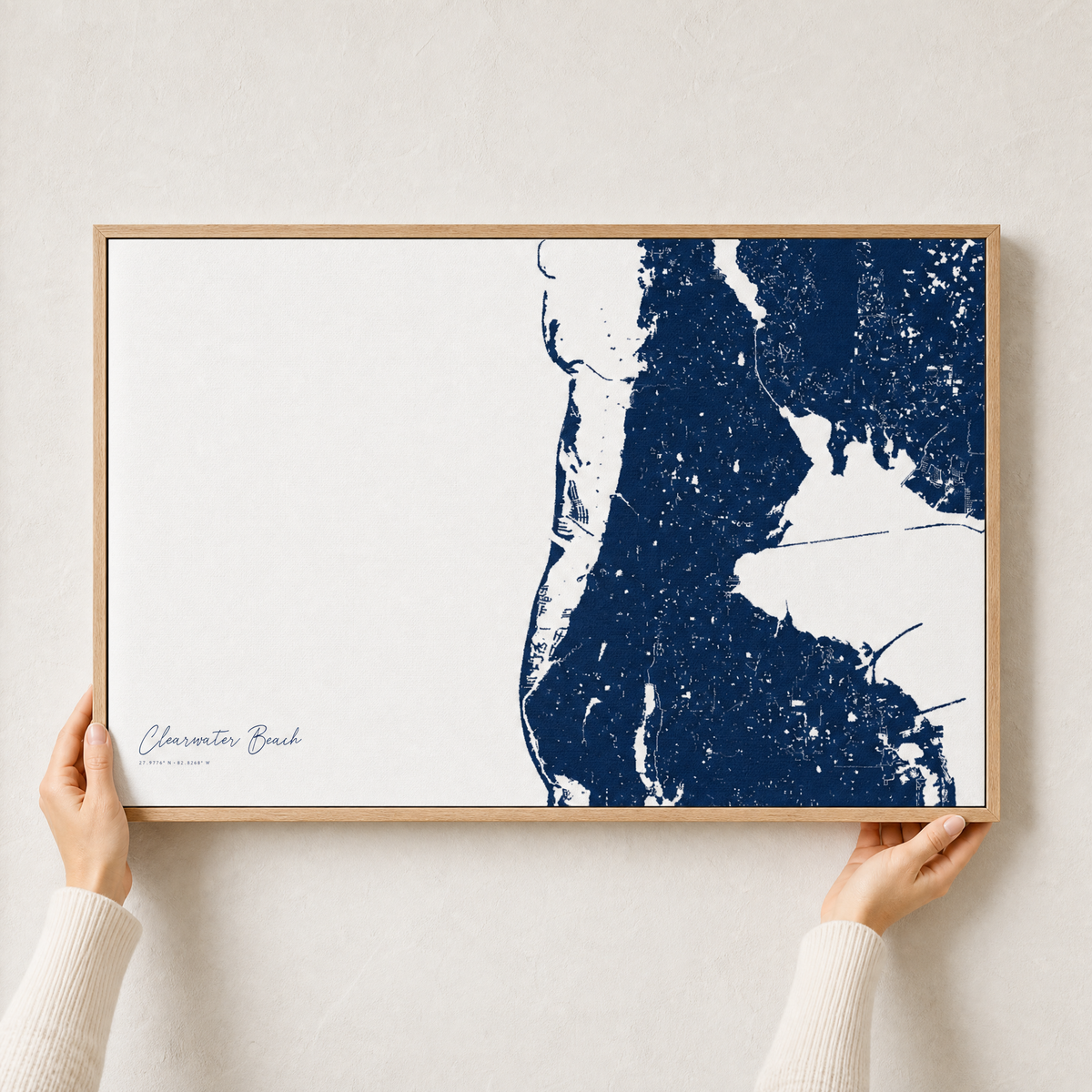 Clearwater Beach canvas map — hands holding the canvas in an oak frame