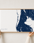 Clearwater Beach canvas map — hands holding the canvas in an oak frame