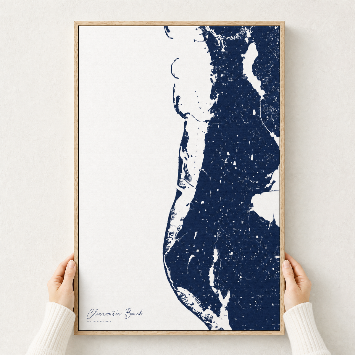 Clearwater Beach canvas map — hands holding the canvas in an oak frame