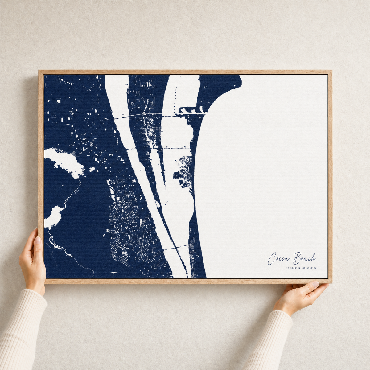 Cocoa Beach canvas map — hands holding the canvas in an oak frame