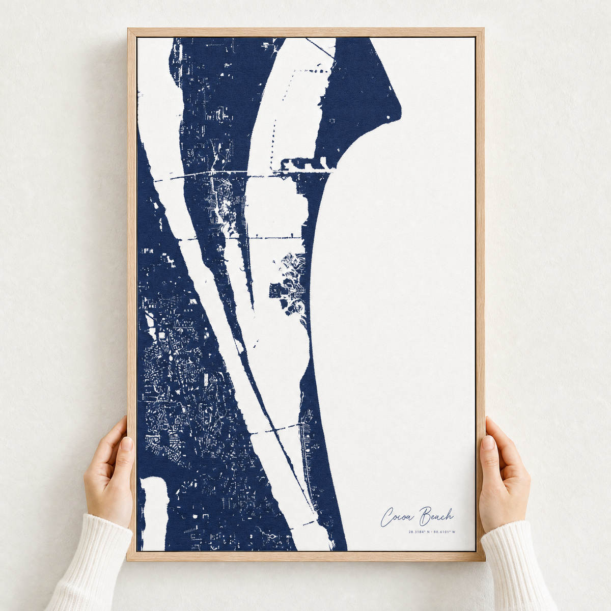 Cocoa Beach canvas map — hands holding the canvas in an oak frame