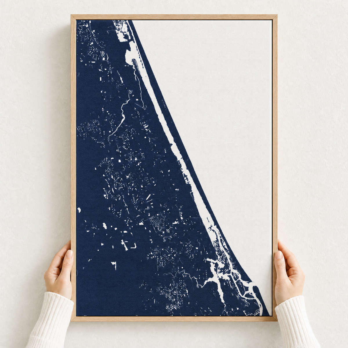 Daytona Beach canvas map — hands holding the canvas in an oak frame