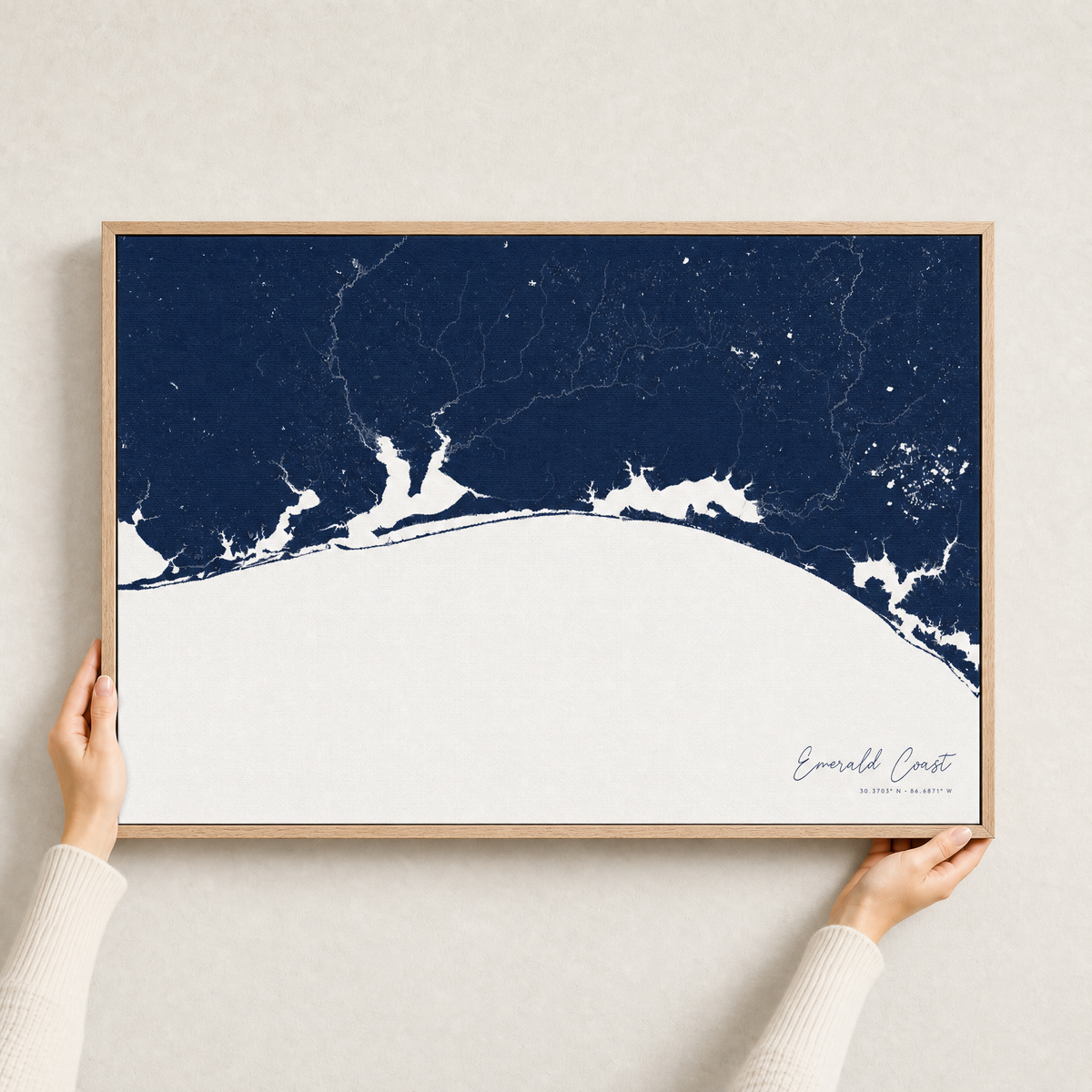 Emerald Coast canvas map — hands holding the canvas in an oak frame