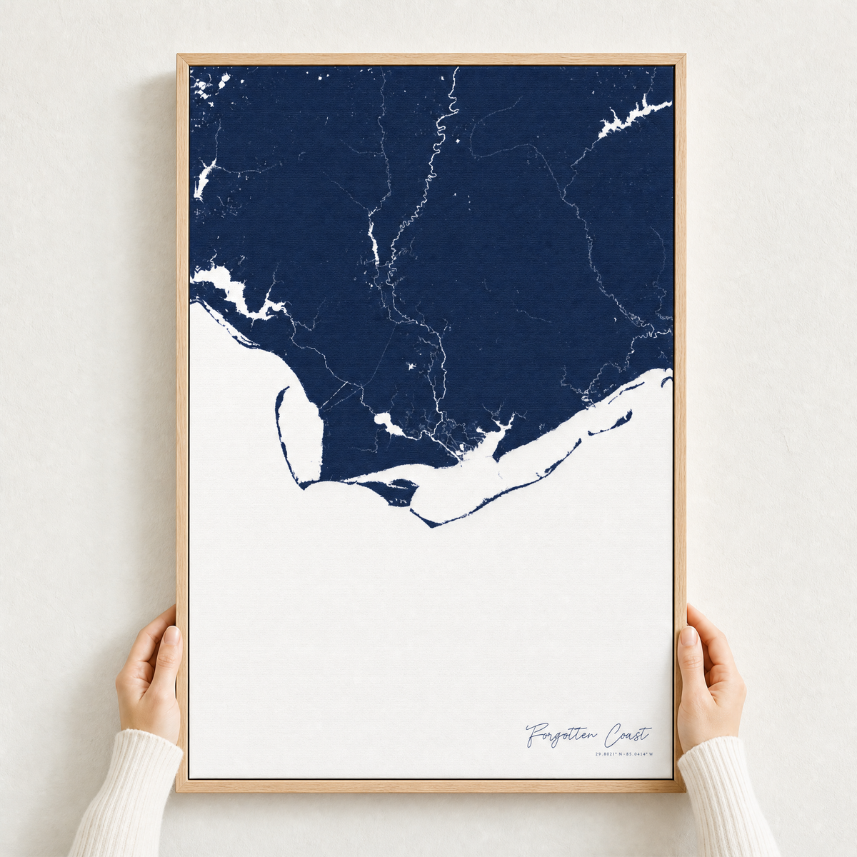 Forgotten Coast canvas map — hands holding the canvas in an oak frame