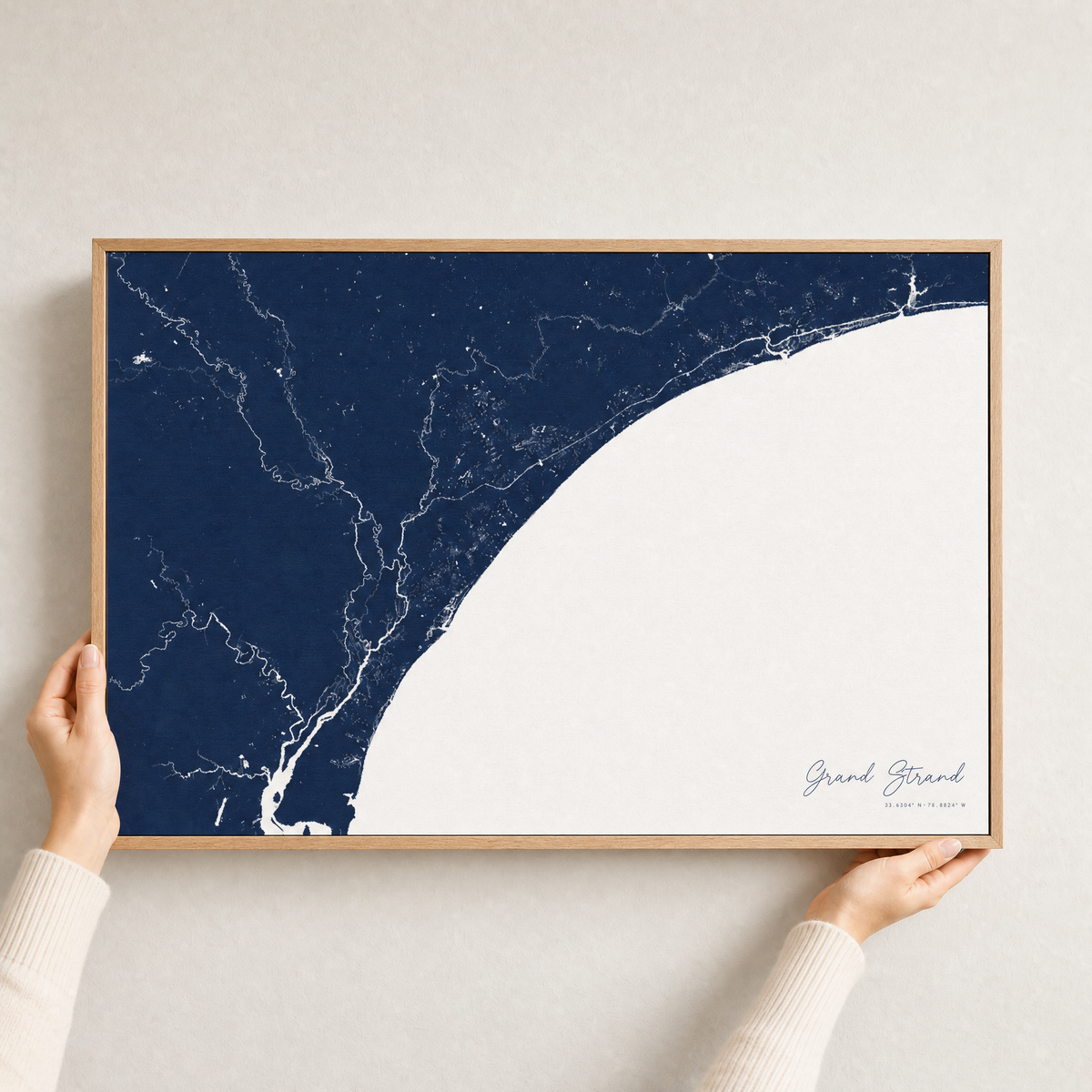 Grand Strand canvas map — hands holding the canvas in an oak frame