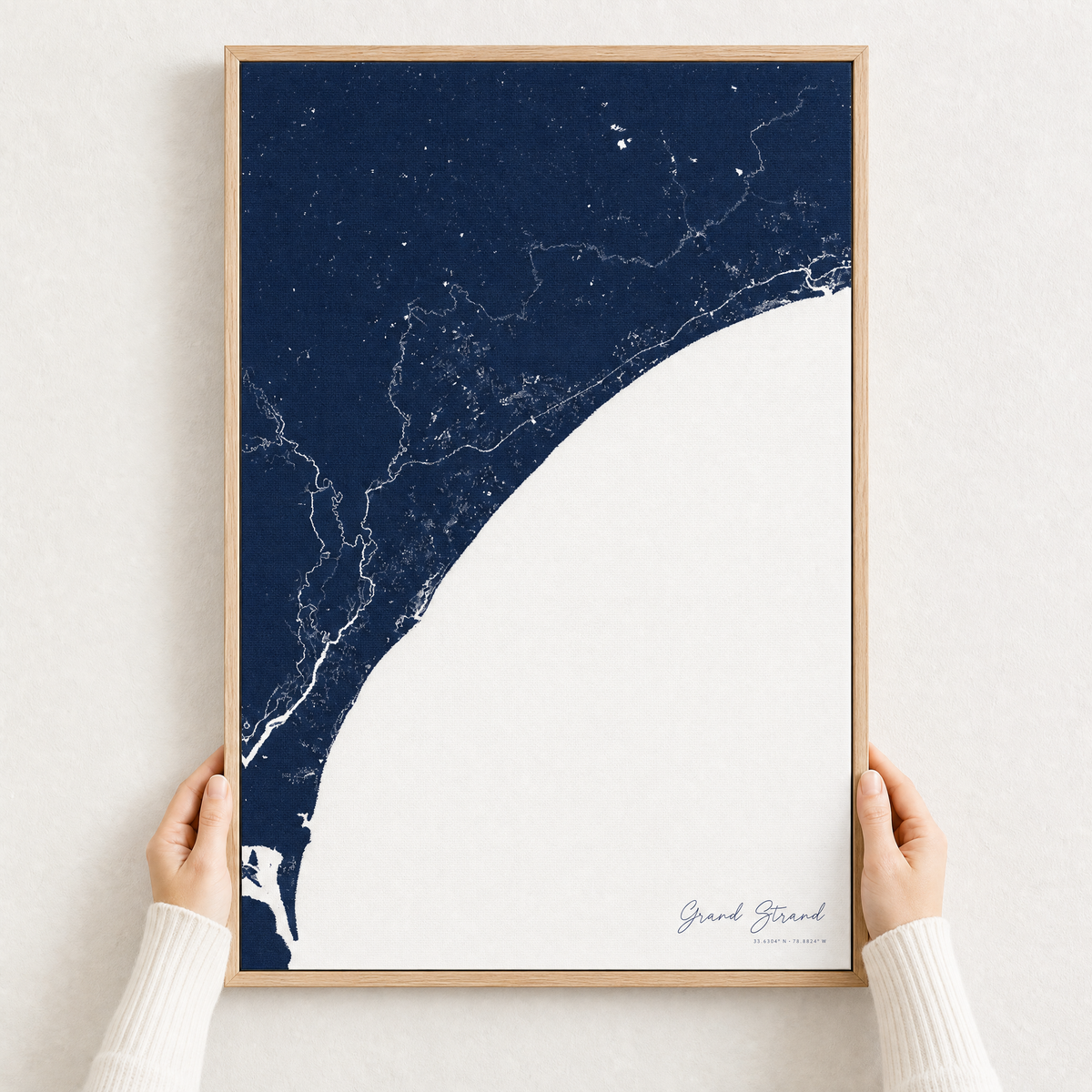 Grand Strand canvas map — hands holding the canvas in an oak frame