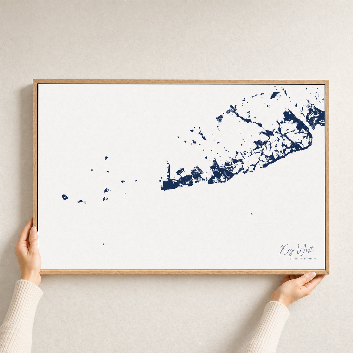 Key West canvas map — hands holding the canvas in an oak frame