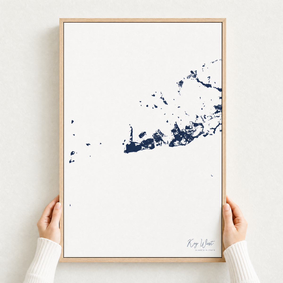 Key West canvas map — hands holding the canvas in an oak frame