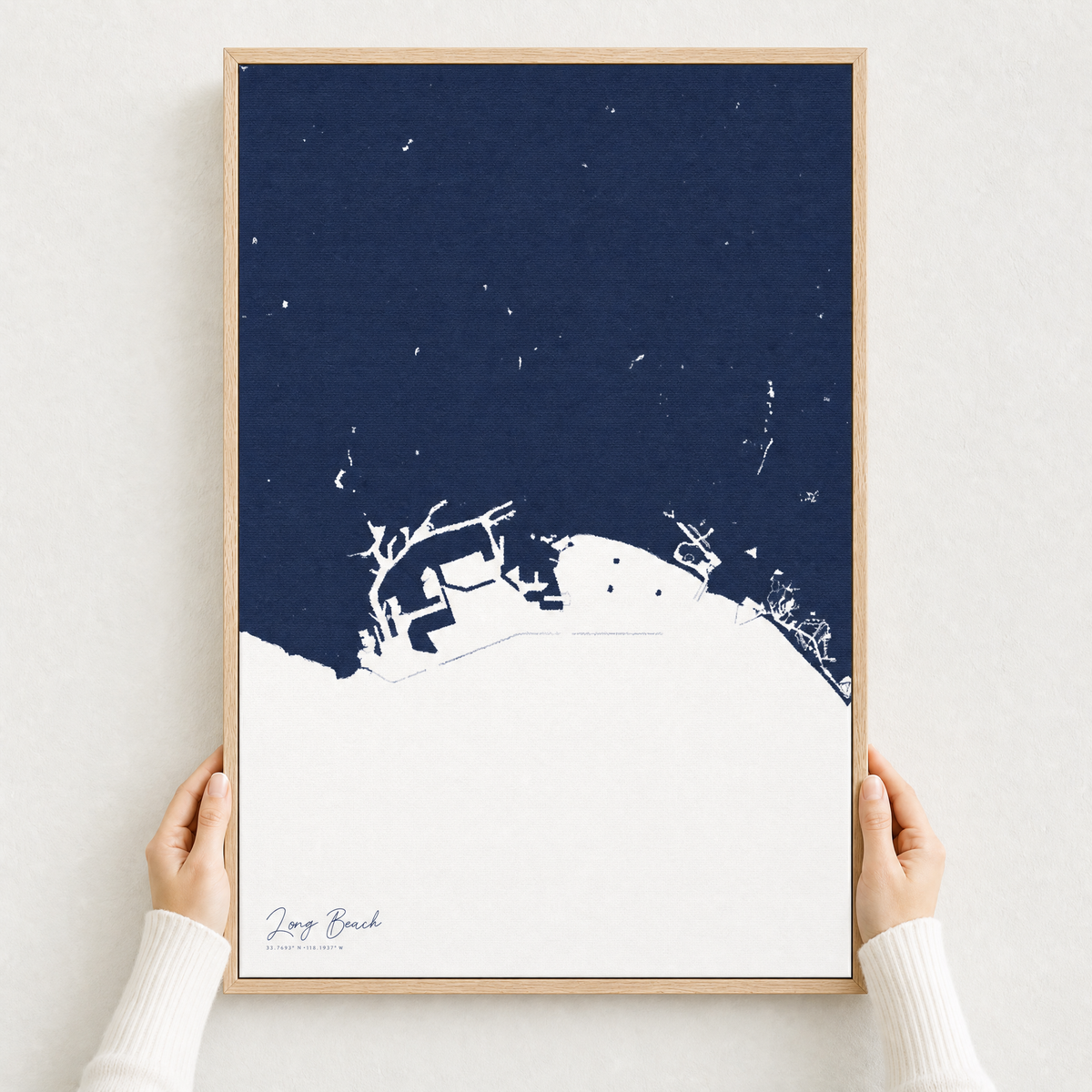 Long Beach canvas map — hands holding the canvas in an oak frame