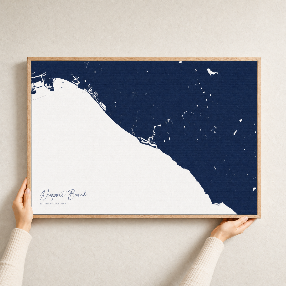 Newport Beach canvas map — hands holding the canvas in an oak frame