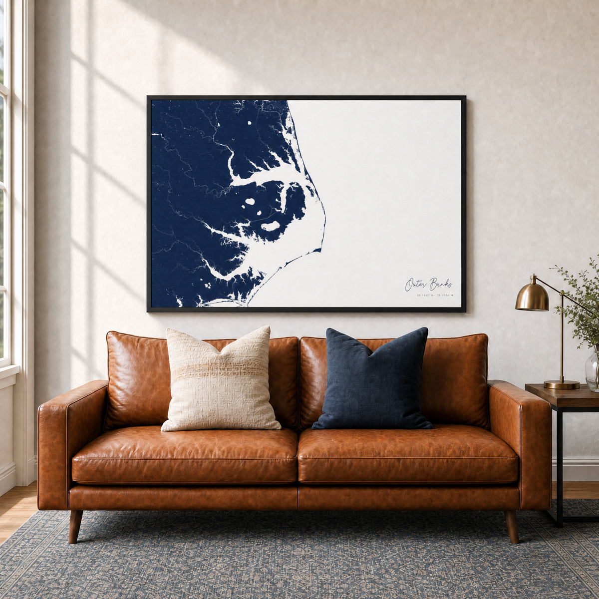 Outer Banks canvas map — two-pillow black-frame sofa interior