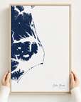 Outer Banks canvas map — hands holding the canvas in an oak frame