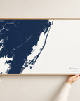 Assateague horizontal canvas map in Navy, hands holding an oak-framed canvas