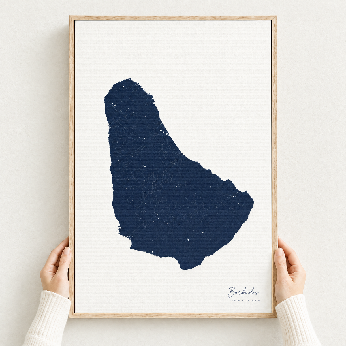Barbados vertical canvas map in Navy, hands holding an oak-framed canvas