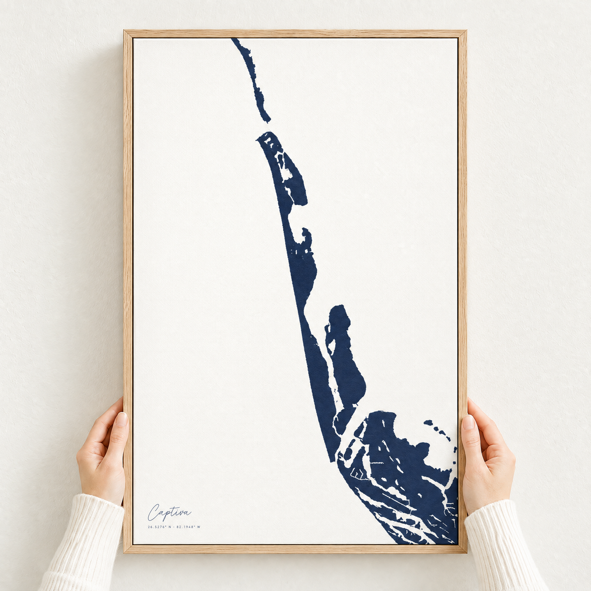 Captiva vertical canvas map in Navy, hands holding an oak-framed canvas