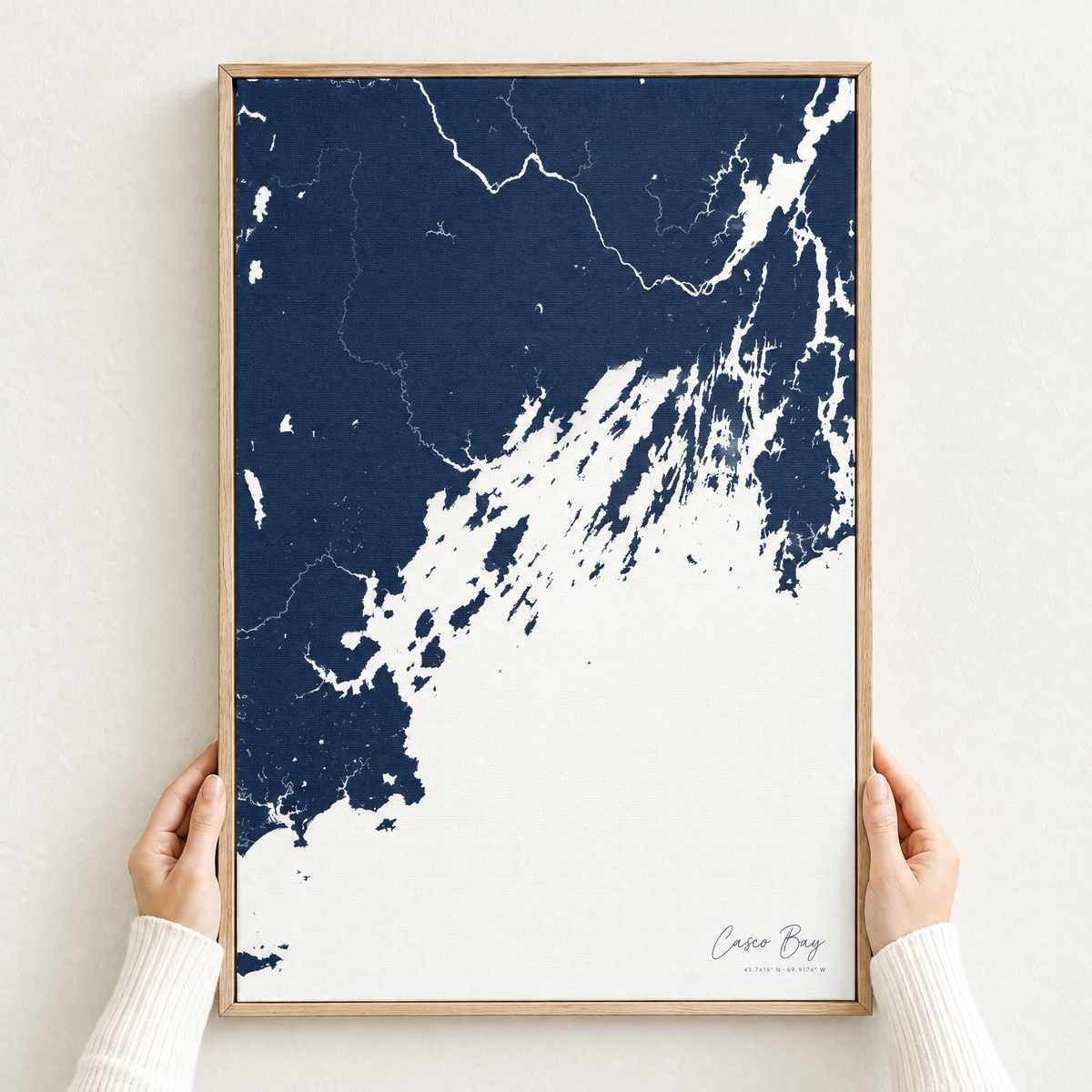 Casco Bay vertical canvas map in Navy, hands holding an oak-framed canvas