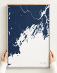 Casco Bay vertical canvas map in Navy, hands holding an oak-framed canvas
