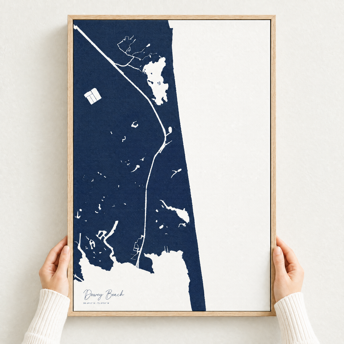 Dewey Beach vertical canvas map in Navy, hands holding an oak-framed canvas