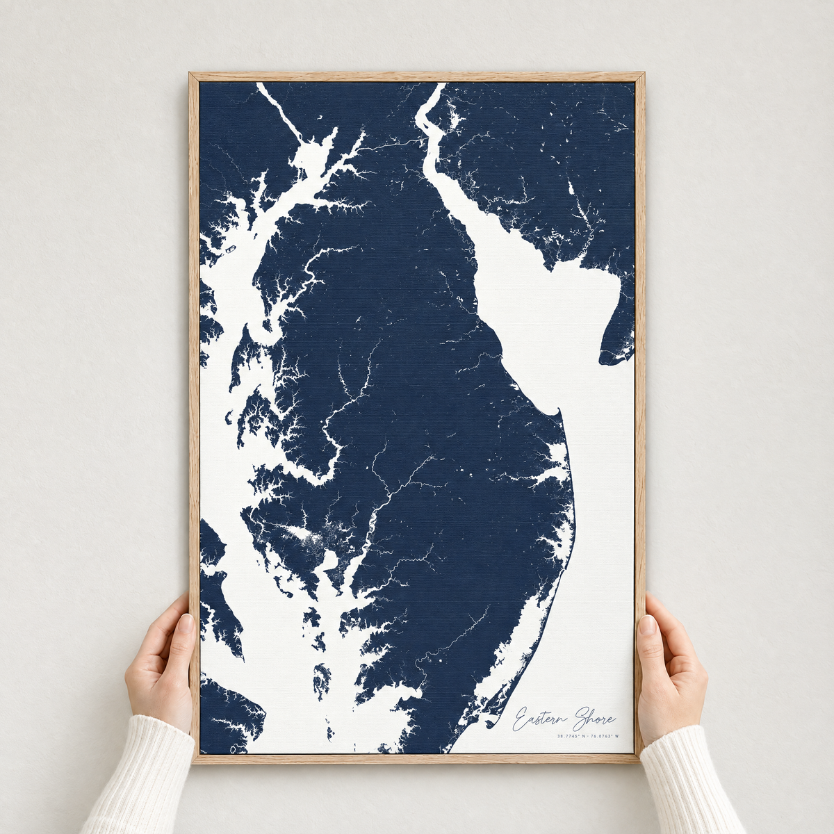 Eastern Shore vertical canvas map in Navy, hands holding an oak-framed canvas