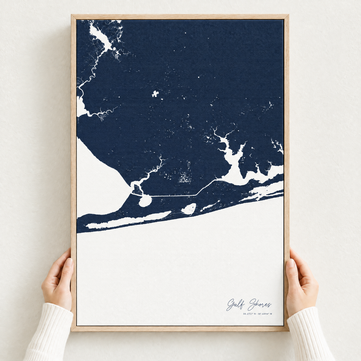 Gulf Shores vertical canvas map in Navy, hands holding an oak-framed canvas