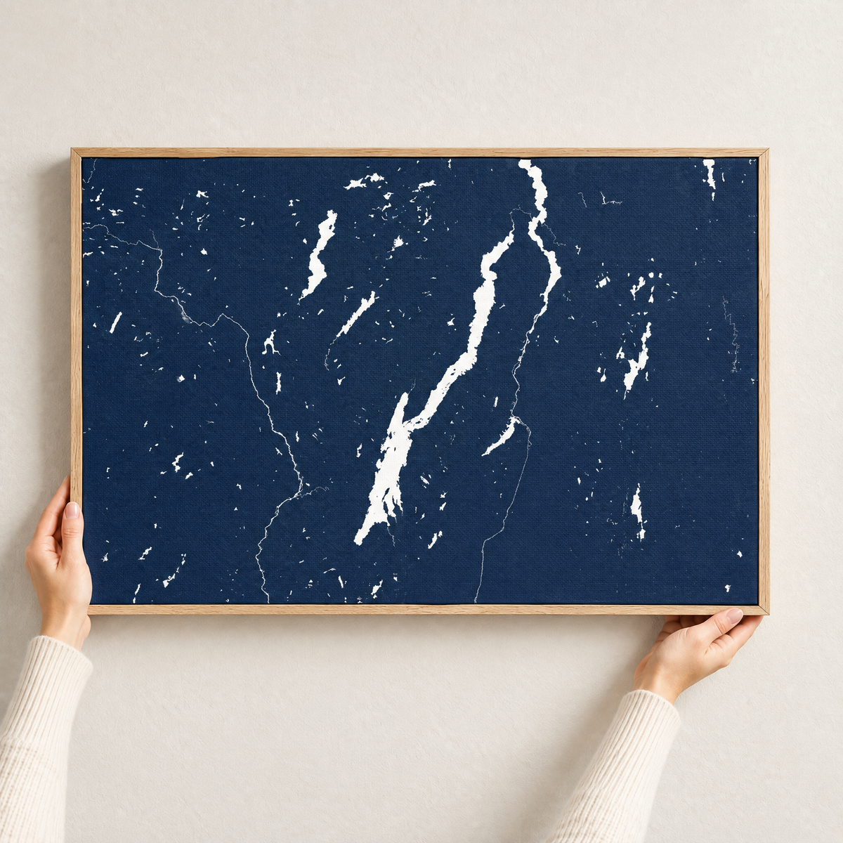 Lake George horizontal canvas map in Navy, hands holding an oak-framed canvas