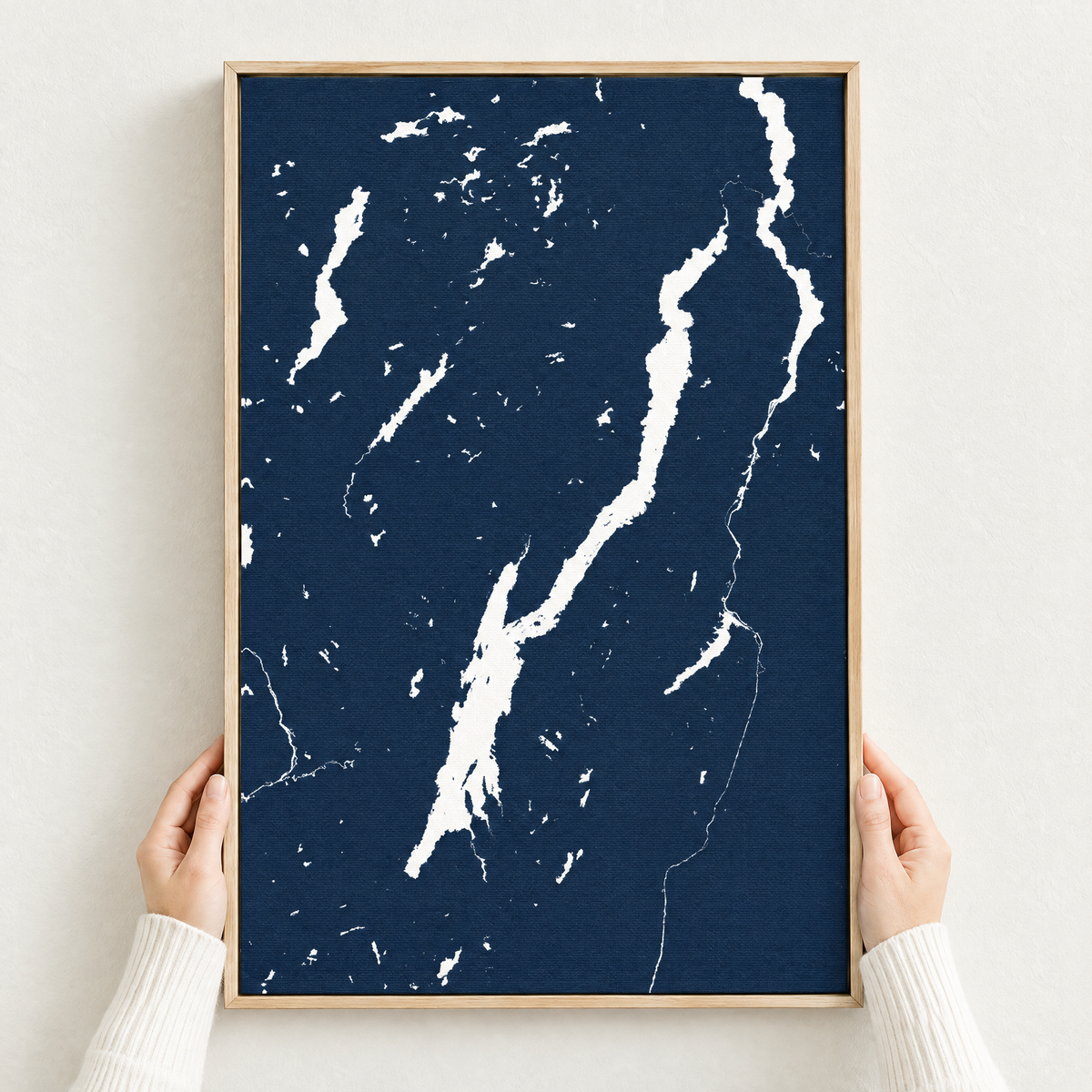 Lake George vertical canvas map in Navy, hands holding an oak-framed canvas