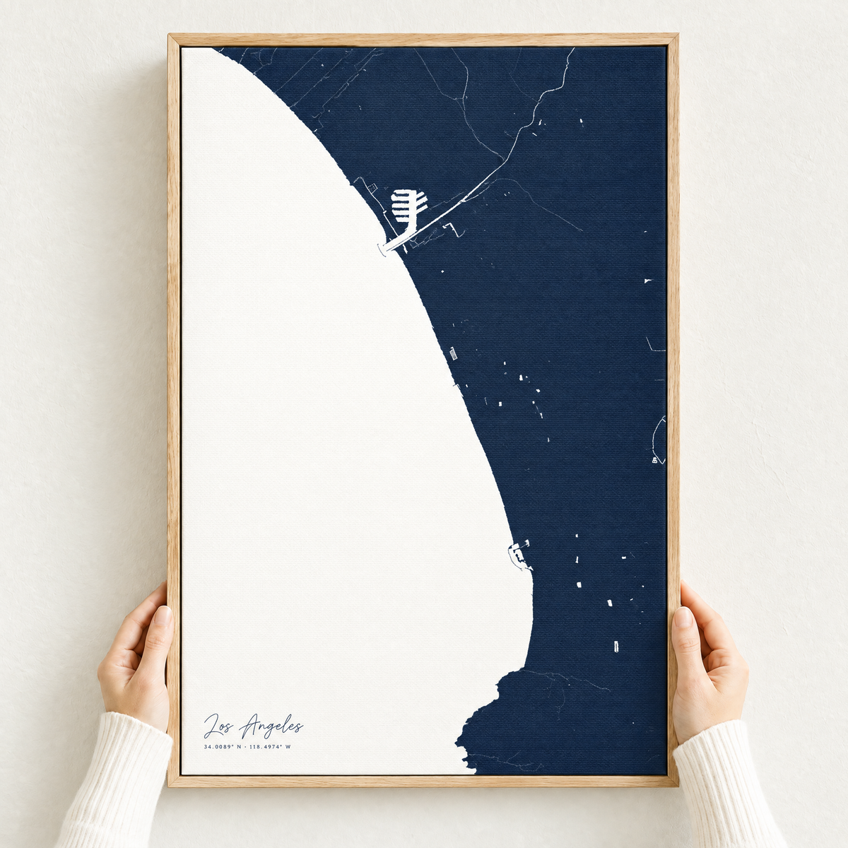 Los Angeles vertical canvas map in Navy, hands holding an oak-framed canvas