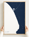 Los Angeles vertical canvas map in Navy, hands holding an oak-framed canvas