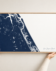 New Smyrna Beach horizontal canvas map in Navy, hands holding an oak-framed canvas