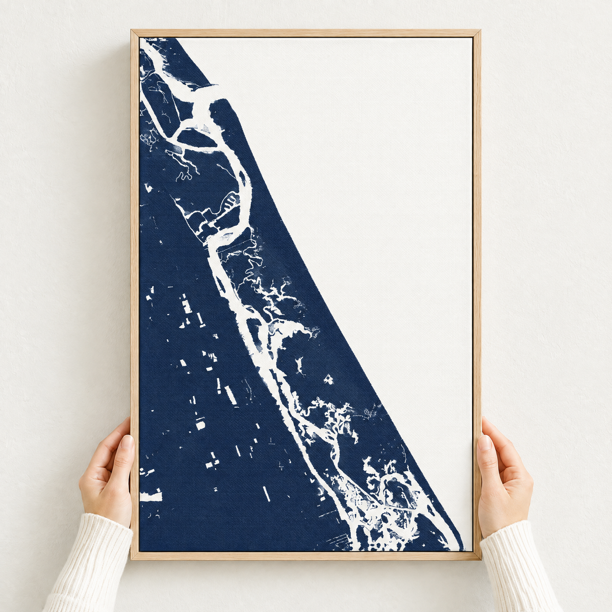 New Smyrna Beach vertical canvas map in Navy, hands holding an oak-framed canvas