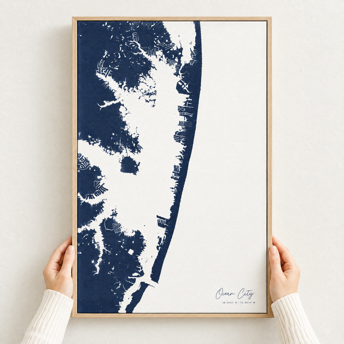 Ocean City vertical canvas map in Navy, hands holding an oak-framed canvas