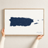 Puerto Rico horizontal canvas map in Navy, hands holding an oak-framed canvas