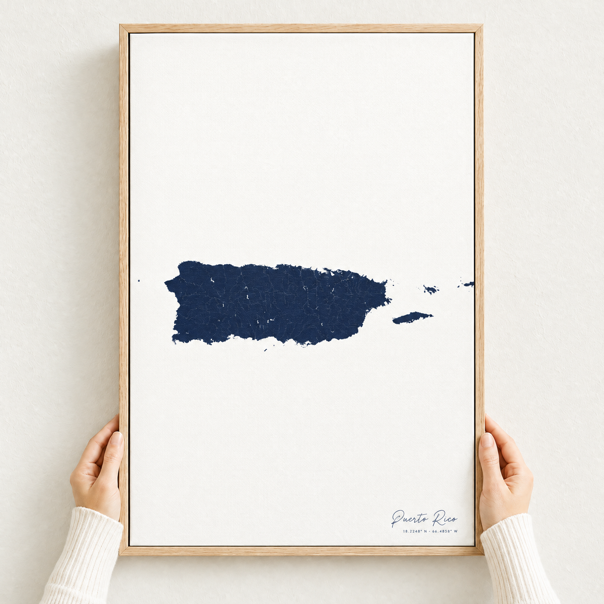 Puerto Rico vertical canvas map in Navy, hands holding an oak-framed canvas