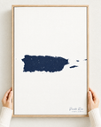 Puerto Rico vertical canvas map in Navy, hands holding an oak-framed canvas
