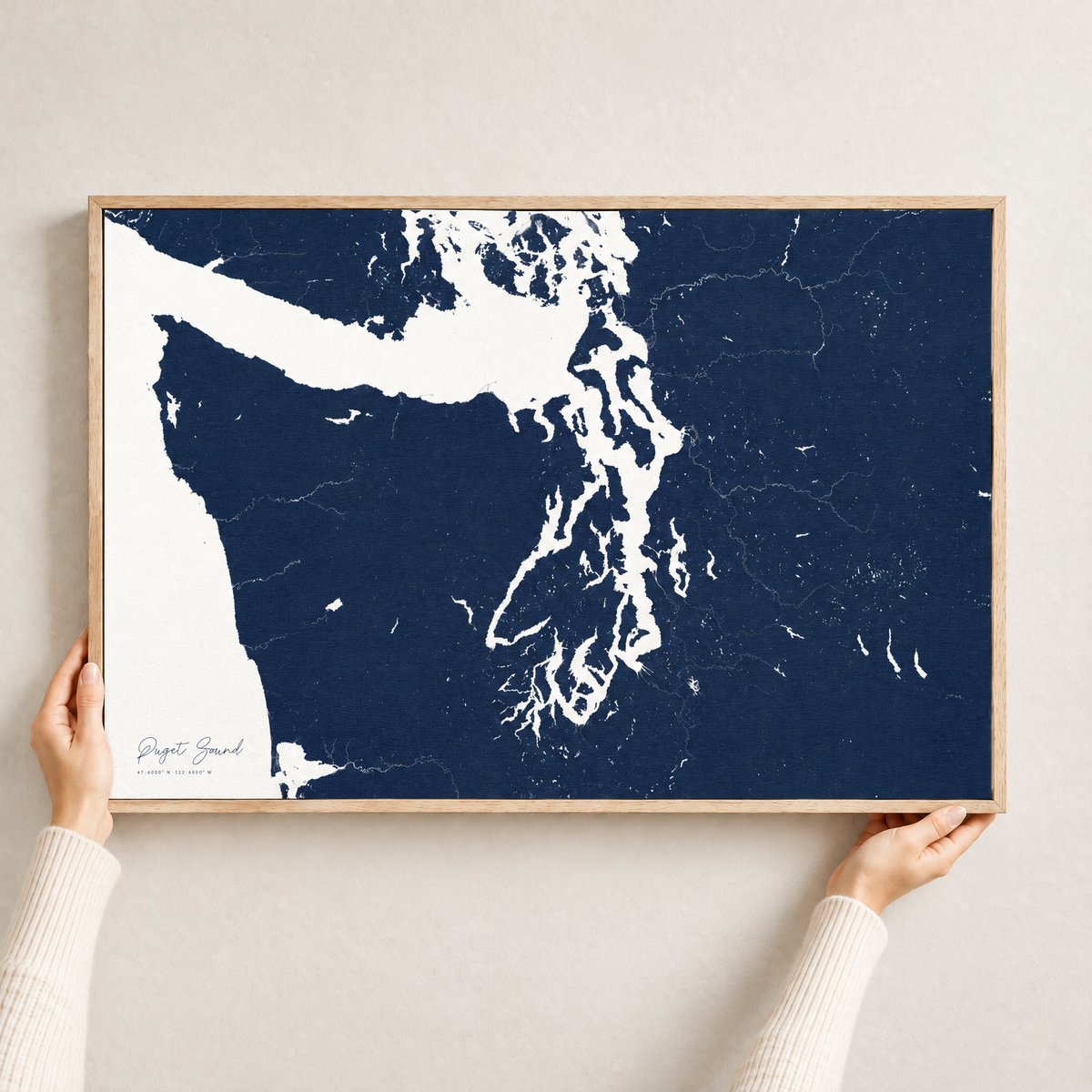 Puget Sound horizontal canvas map in Navy, hands holding an oak-framed canvas
