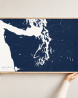 Puget Sound horizontal canvas map in Navy, hands holding an oak-framed canvas