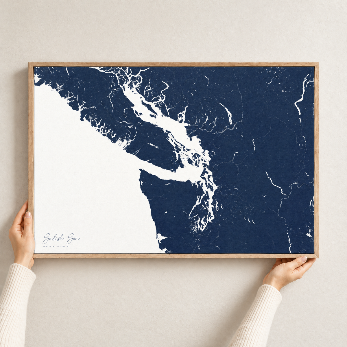 Salish Sea horizontal canvas map in Navy, hands holding an oak-framed canvas