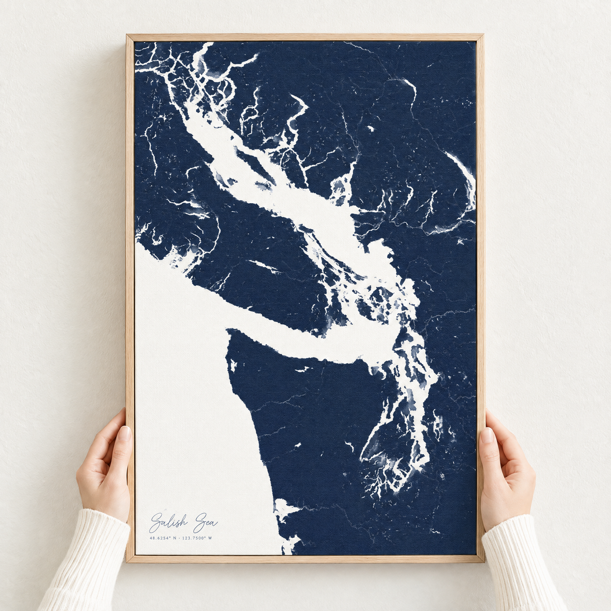 Salish Sea vertical canvas map in Navy, hands holding an oak-framed canvas