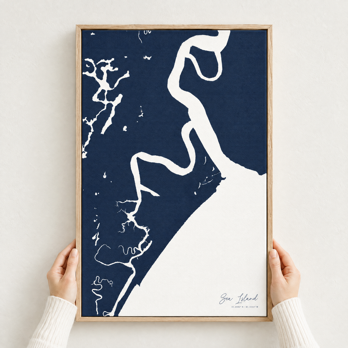 Sea Island vertical canvas map in Navy, hands holding an oak-framed canvas