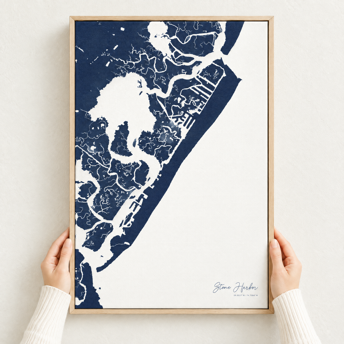 Stone Harbor vertical canvas map in Navy, hands holding an oak-framed canvas