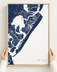 Stone Harbor vertical canvas map in Navy, hands holding an oak-framed canvas