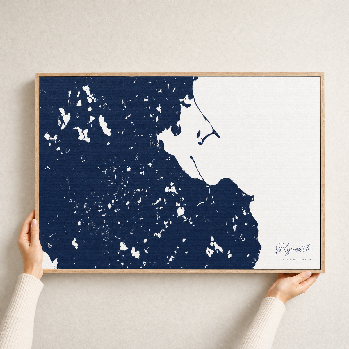 Plymouth canvas map — hands holding the canvas in an oak frame