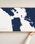 San Francisco canvas map — hands holding the canvas in an oak frame