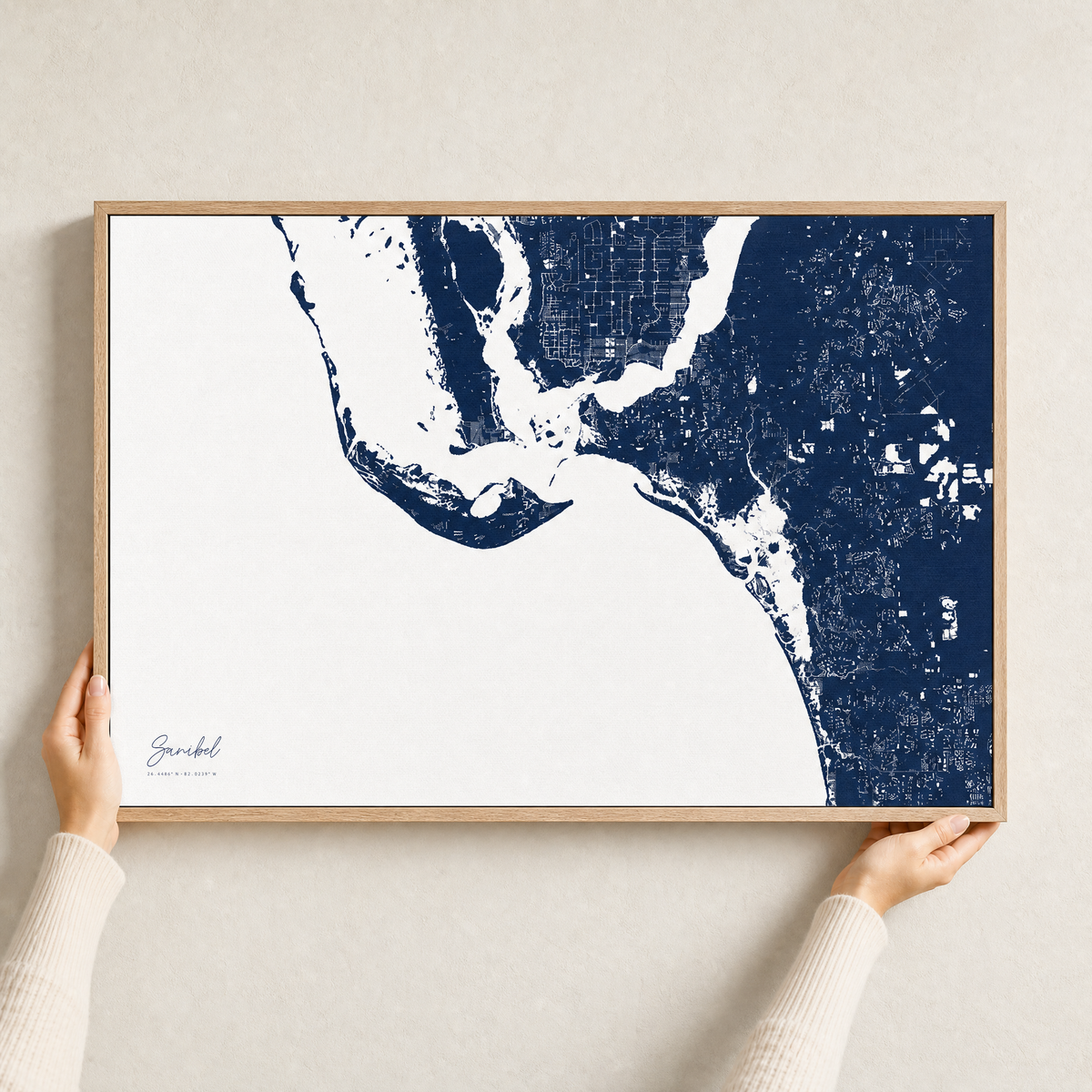 Sanibel canvas map — hands holding the canvas in an oak frame